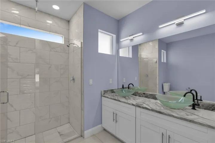 Bathroom featuring tile patterned flooring, vanity, and a shower with door