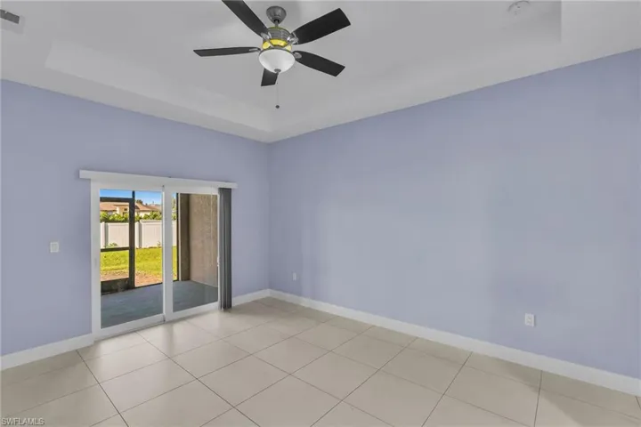 Spare room with a raised ceiling, ceiling fan, and light tile patterned flooring