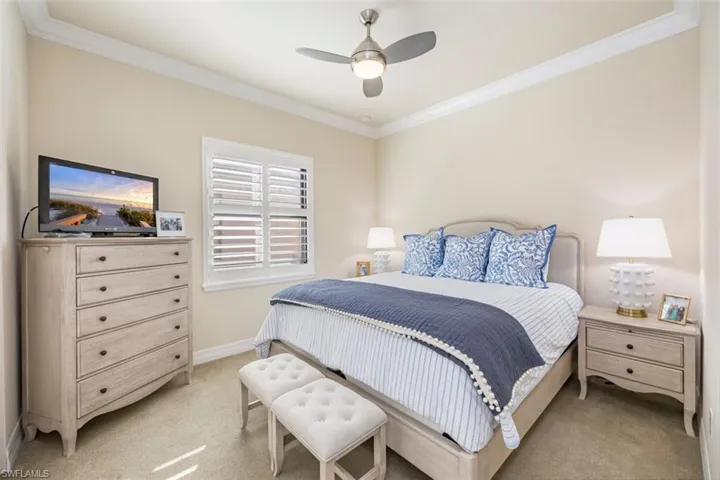 Carpeted bedroom featuring crown molding and ceiling fan