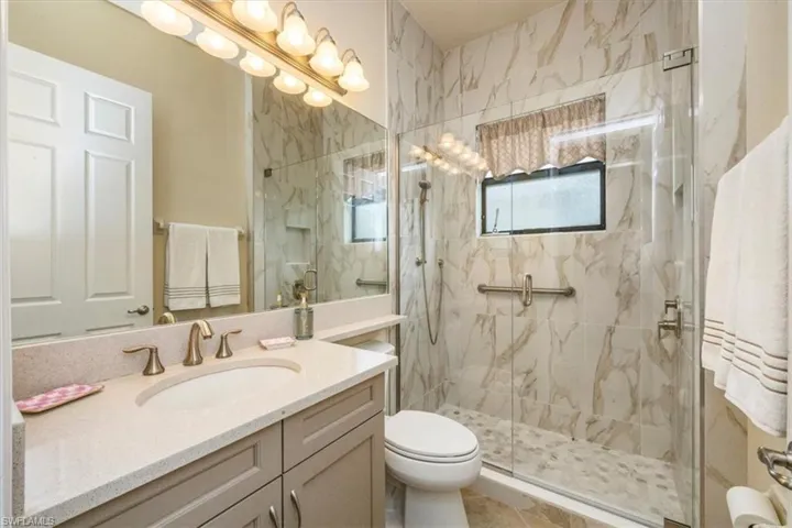 Bathroom featuring vanity and a marble finish shower