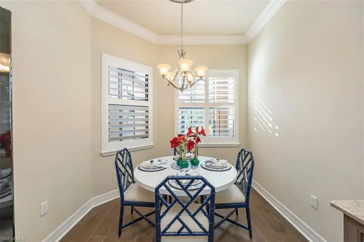 Dining space featuring dark wood-style floors, crown molding, and a chandelier