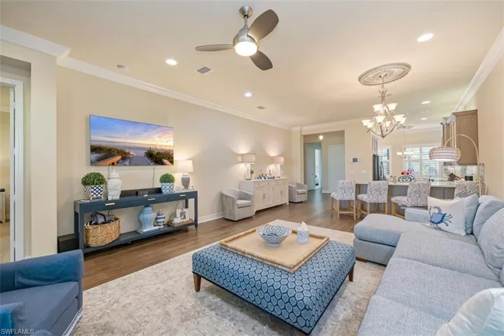 Living room featuring wood finished floors, ceiling fan, crown molding, a chandelier, and recessed lighting