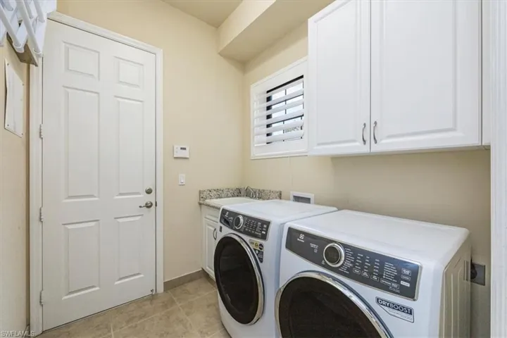 Laundry room featuring cabinet space, washer and clothes dryer, and light tile patterned flooring