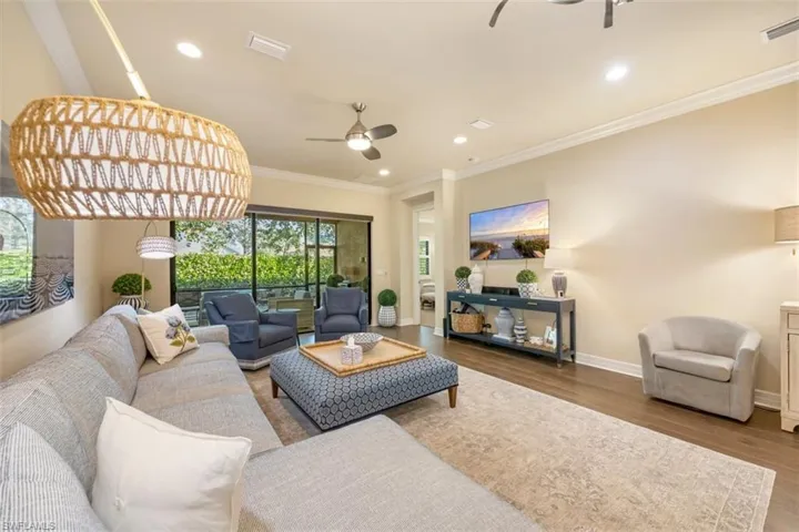 Living room with wood finished floors, ornamental molding, a ceiling fan, and recessed lighting