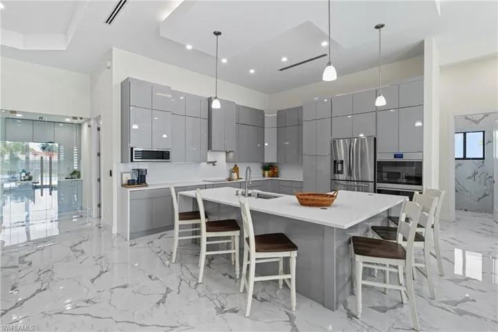Kitchen featuring gray cabinets, pendant lighting, light marble finish floors, modern cabinets, and a breakfast bar