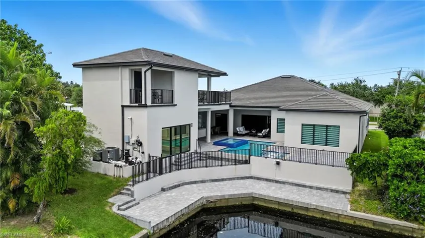 Back of house with a patio area, stucco siding, a balcony, a fenced backyard, and a pool with connected hot tub