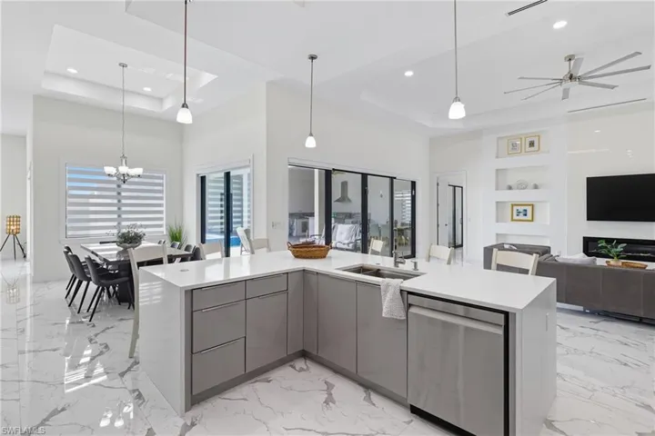 Kitchen featuring modern cabinets, open floor plan, light marble finish flooring, a raised ceiling, and gray cabinets
