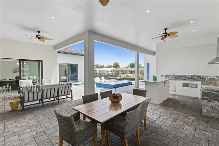 View of patio / terrace featuring ceiling fan, an outdoor pool, an outdoor kitchen, and outdoor dining space