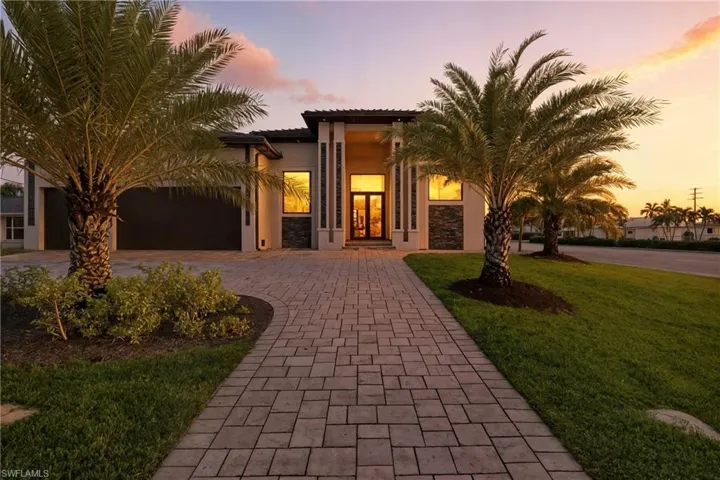 Mediterranean / spanish-style home with decorative driveway, a tiled roof, a yard, stucco siding, and an attached garage