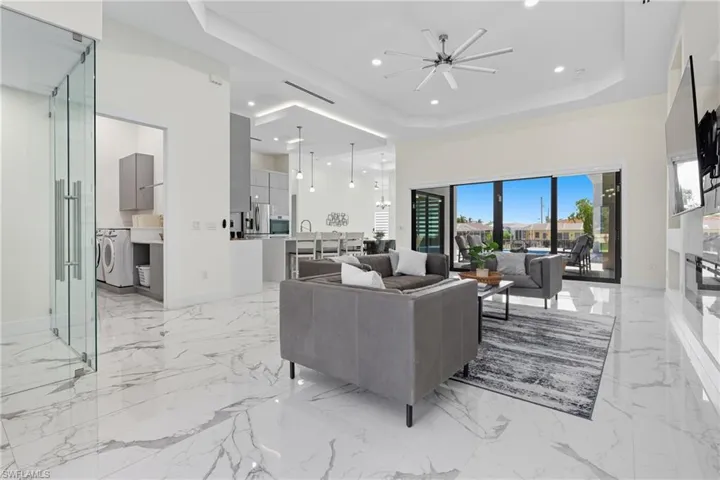 Living room with a raised ceiling, light marble finish floors, recessed lighting, washer / clothes dryer, and a high ceiling