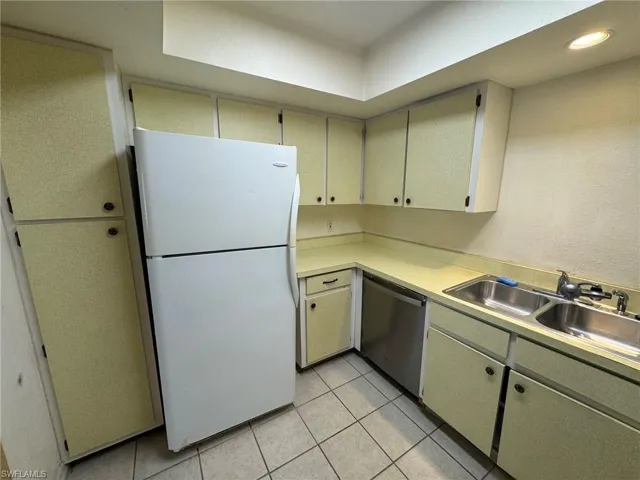 Kitchen featuring extensive cabinetry, L-shaped countertop, stainless steel double basin sink, and a stainless steel dishwasher.