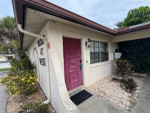 Stucco exterior with a bold magenta entry door.