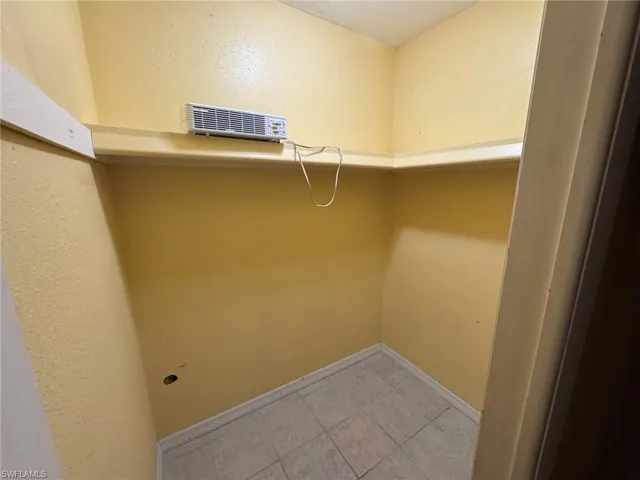 Primary bedroom interior space featuring light yellow textured walls and light-colored tile flooring
