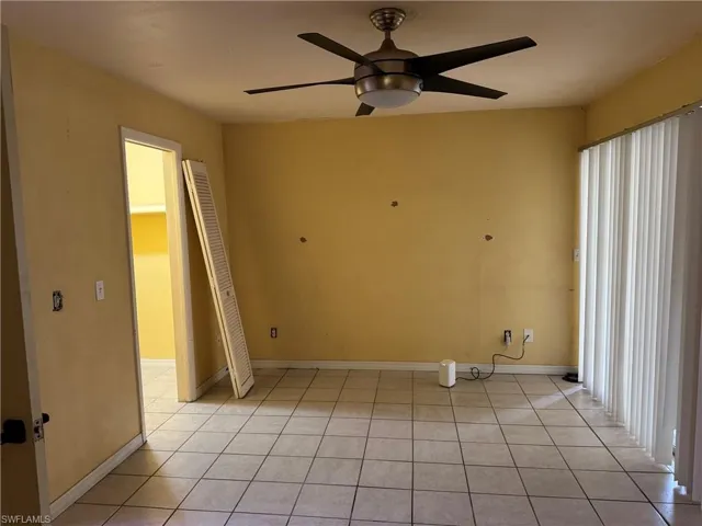 Primary Bedroom ,Ceramic tile flooring, a ceiling fan with integrated lighting, and vertical blinds on the sliding glass door to lanai.