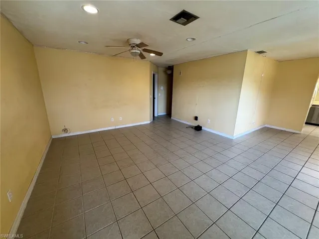 Spacious living room featuring neutral-toned tile flooring, recessed ceiling lighting, and a ceiling fan with integrated illumination