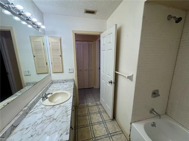 Bathroom featuring a single vanity with an integrated sink, patterned countertop, and a full-width mirror