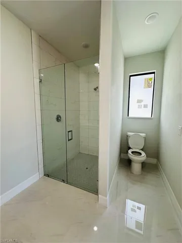 Bathroom featuring tile floors, an enclosed shower, and toilet