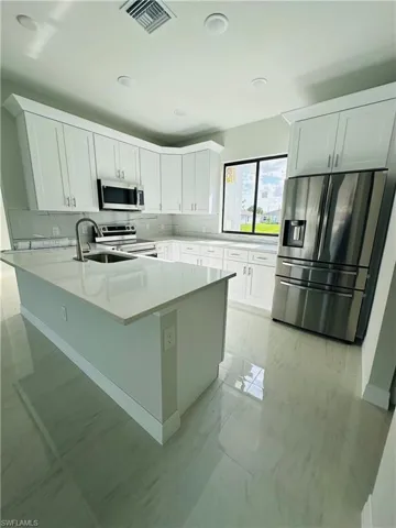 Kitchen with white cabinets, appliances with stainless steel finishes, backsplash, and light tile floors