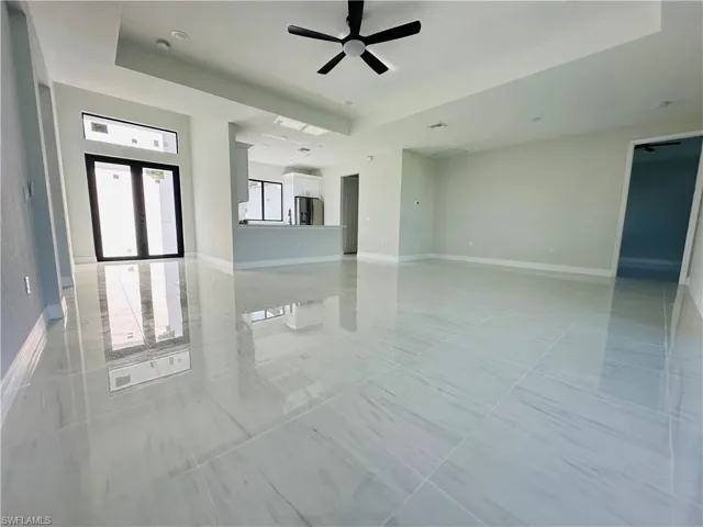 Unfurnished room featuring light tile floors, ceiling fan, and a raised ceiling
