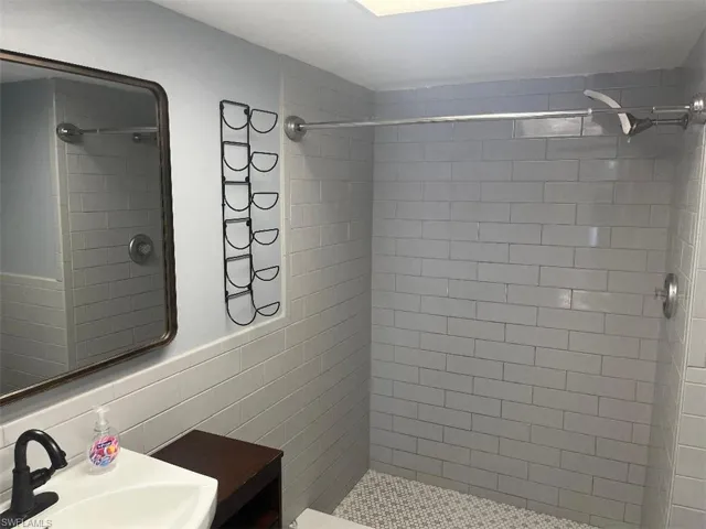 Bathroom featuring a shower stall, vanity, and tile walls