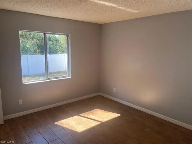 Empty room featuring dark wood-type flooring and a textured ceiling