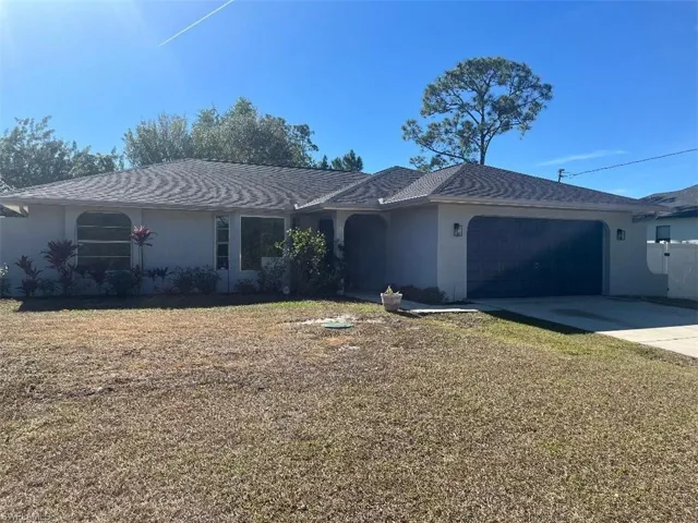Ranch-style home with stucco siding, concrete driveway, an attached garage, and a front lawn