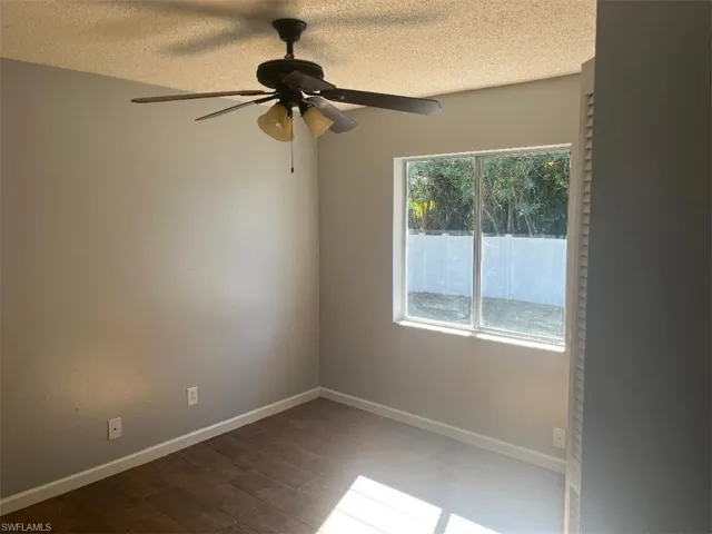 Empty room with a textured ceiling, wood finished floors, and a ceiling fan