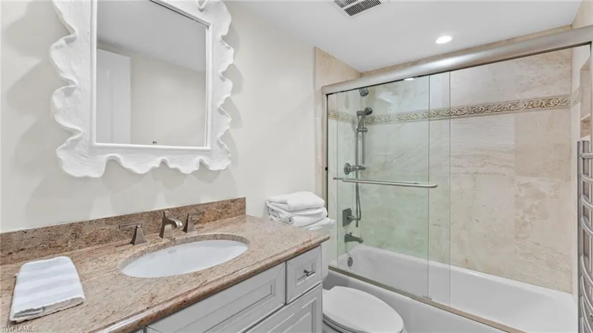 Full bathroom with vanity, combined bath / shower with glass door, and toilet