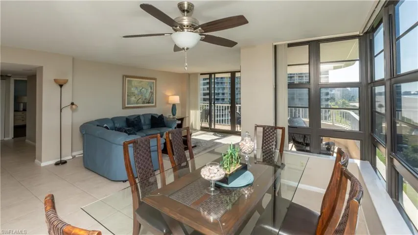 Dining area with a wall of windows, ceiling fan, and light tile patterned flooring