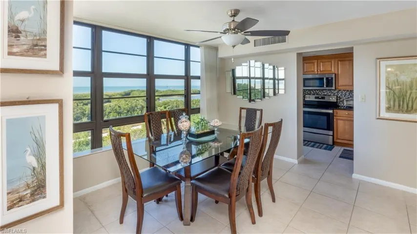 Dining space featuring light tile patterned floors, a ceiling fan, and a water view