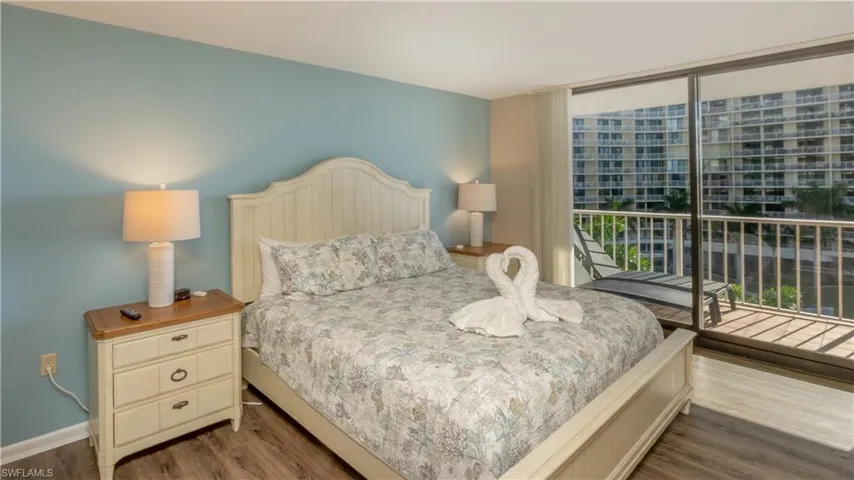 Bedroom featuring access to exterior, dark wood-type flooring, and expansive windows