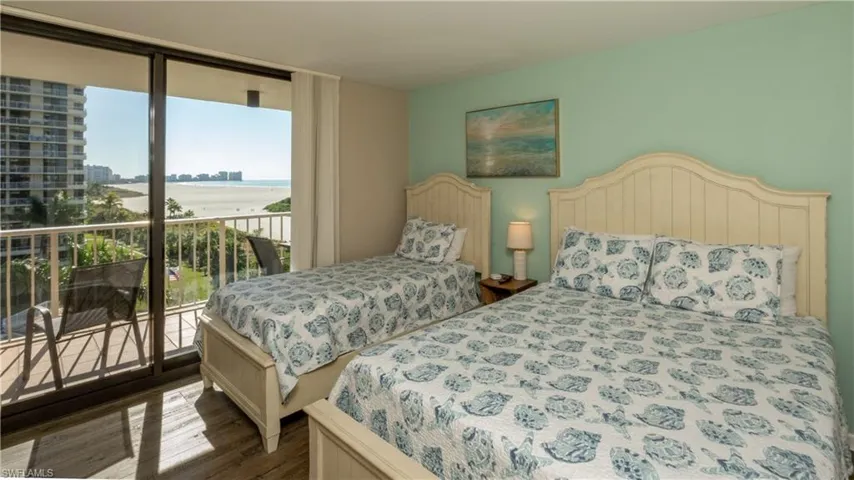 Bedroom with expansive windows, a water view, access to exterior, and dark wood finished floors