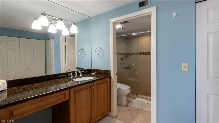 Full bath featuring vanity, a stall shower, a closet, and light tile patterned floors