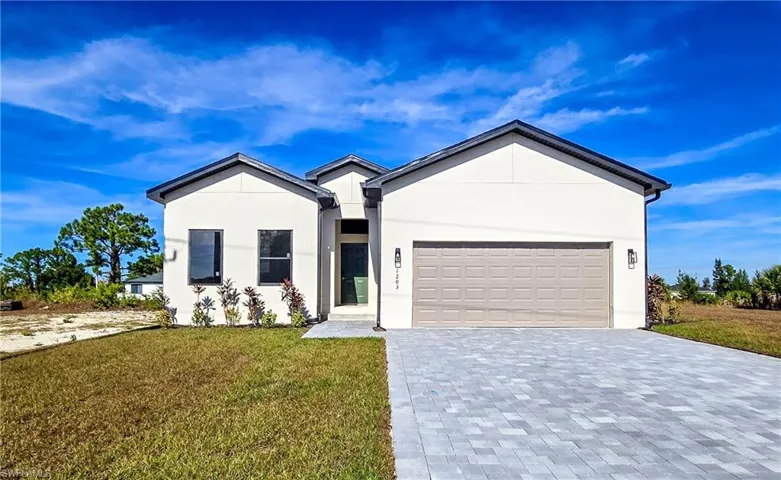 Single story home featuring decorative driveway, a front lawn, stucco siding, and a garage