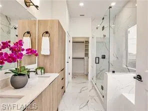 Bathroom with double vanity, a marble style finish shower, light marble finish flooring, recessed lighting, and a spacious closet (Model Home) glass enclosure not included