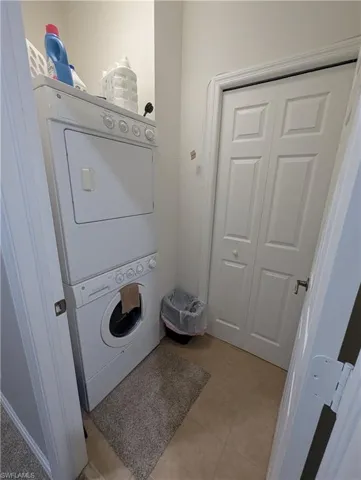 Clothes washing area featuring stacked washer / dryer, laundry area, and light tile patterned floors