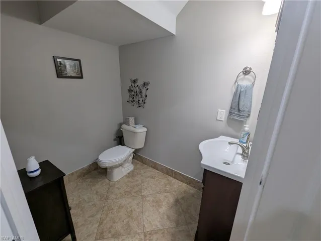 Half bath featuring tile patterned flooring, toilet, vanity, and baseboards
