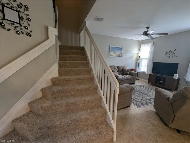 Staircase featuring visible vents, tile patterned floors, and ceiling fan