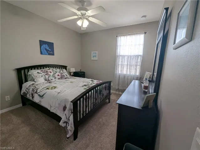 Carpeted bedroom featuring a ceiling fan and baseboards