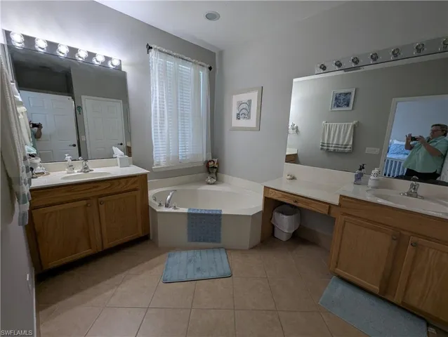 Full bathroom featuring two vanities, tile patterned floors, and a sink