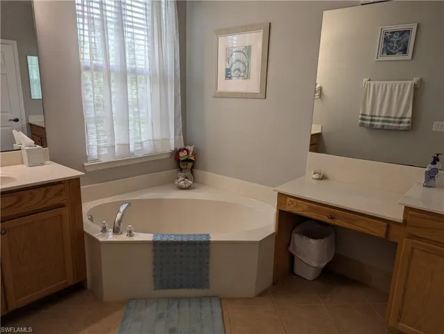 Full bath with tile patterned floors, a garden tub, and vanity