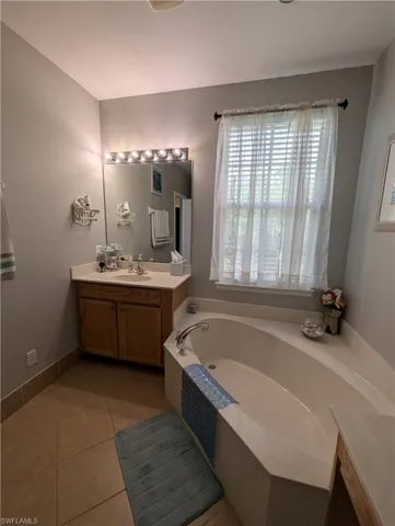 Bathroom with a bath, tile patterned floors, vanity, and a wealth of natural light