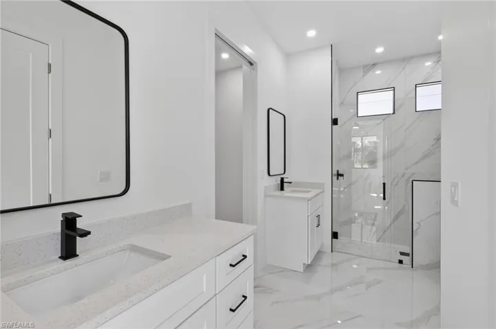 Bathroom with a marble finish shower, two vanities, recessed lighting, and light marble finish floors