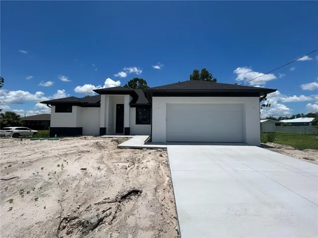 Prairie-style house with an attached garage, stucco siding, and driveway