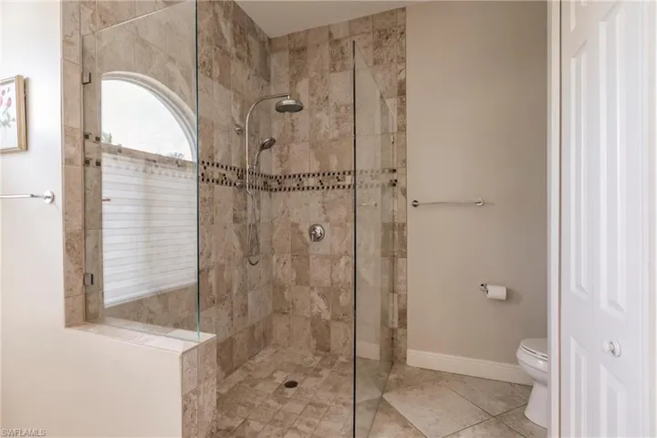 Bathroom featuring a tile shower, tile flooring, and toilet
