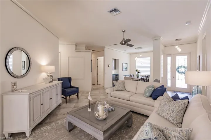 Living room with tile flooring, ornamental molding, and ceiling fan