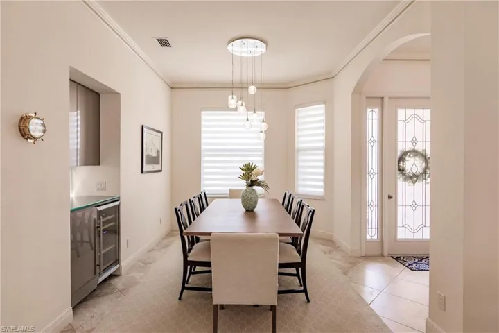 Dining space featuring ornamental molding, light tile flooring, and wine cooler