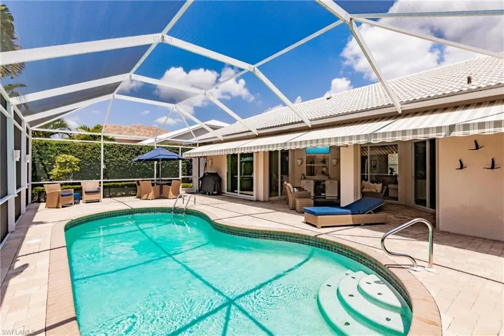 View of pool with glass enclosure and a patio area