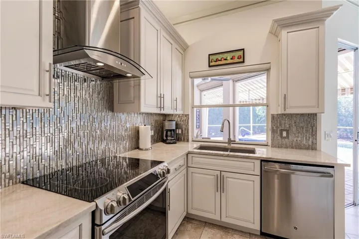 Kitchen with a wealth of natural light, wall chimney exhaust hood, stainless steel appliances, and tasteful backsplash