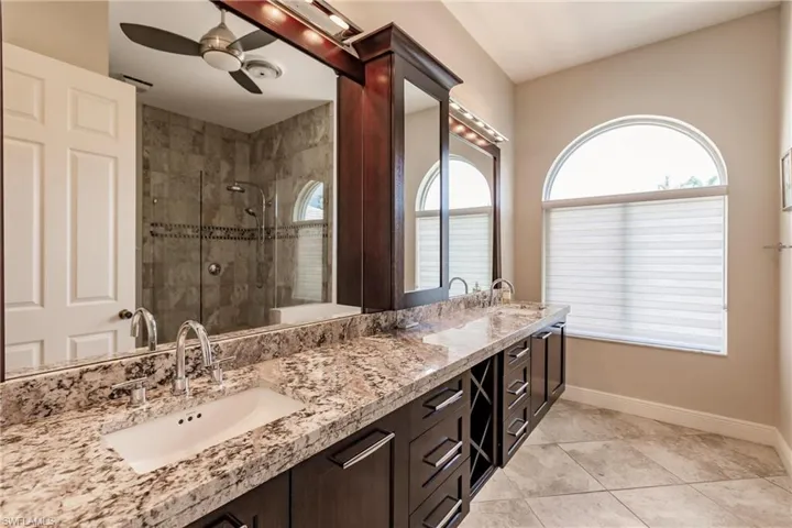Bathroom with tile flooring, ceiling fan, oversized vanity, and dual sinks